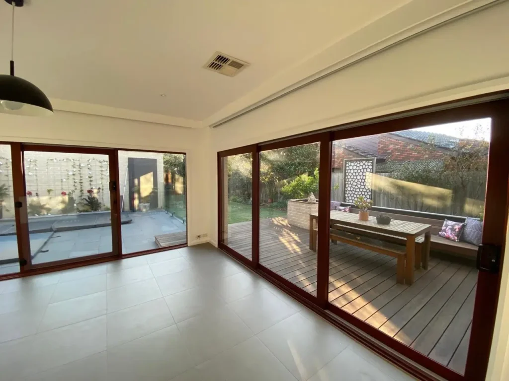 Professionally painted bright living room featuring crisp white walls and clean ceilings, showcasing large timber sliding glass doors that open to a backyard deck.