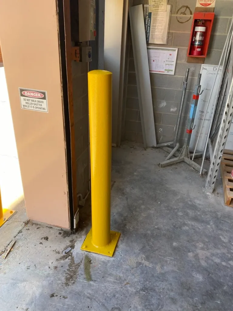 A newly painted high-visibility safety yellow metal bollard in a commercial warehouse in Melbourne CBD by EQ Painting Solutions.