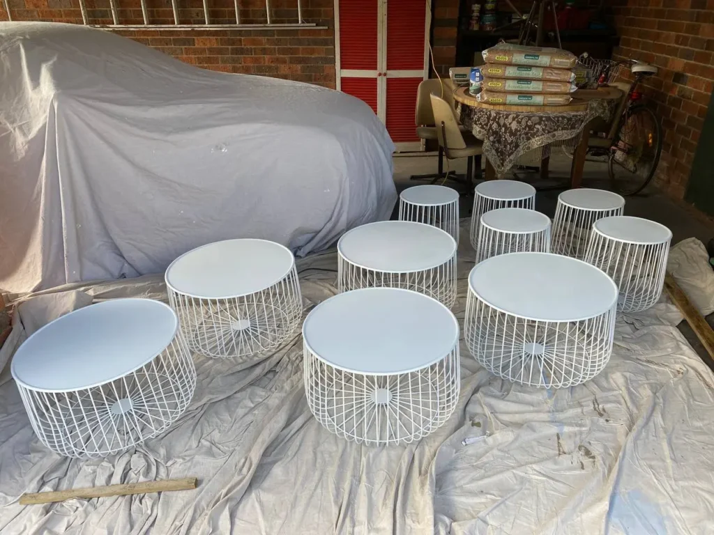 A collection of newly spray-painted white metal wire coffee tables in Melbourne CBD by EQ Painting Solutions.