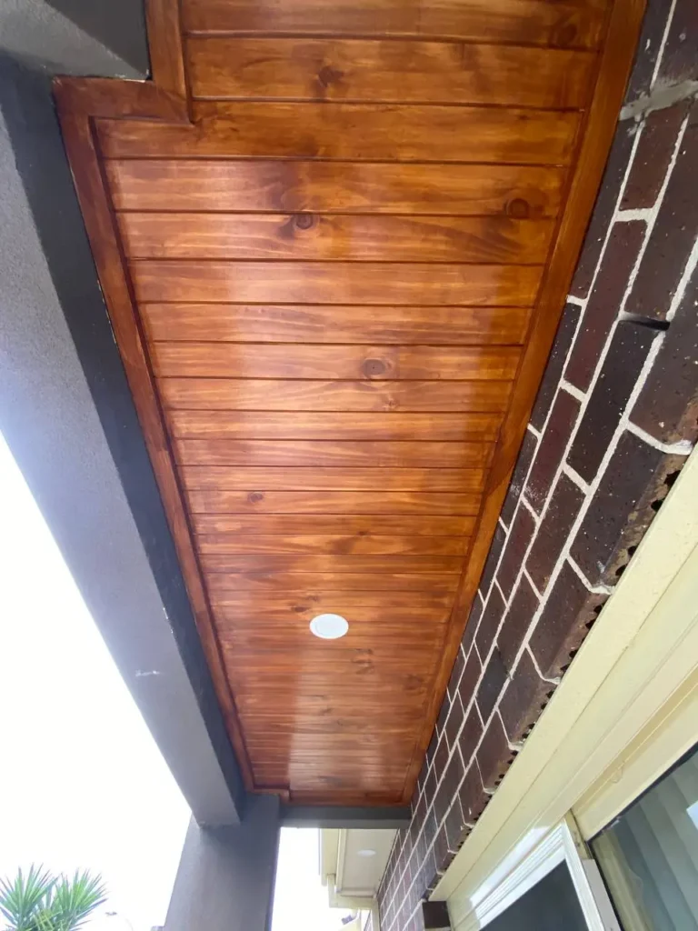 Freshly stained timber ceiling lining on an outdoor alfresco area with a rich natural wood finish completed by professional painters in Melbourne.